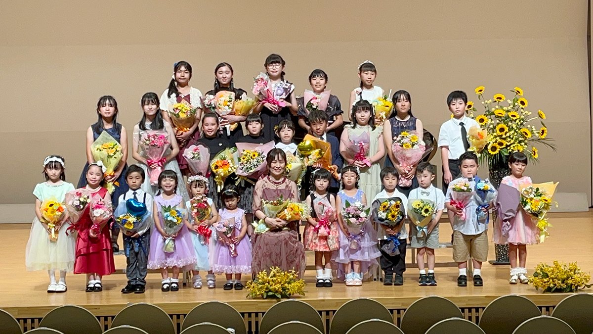 教室の窓辺に置かれたピアノと丸椅子、楽譜が開かれた明るいレッスン室