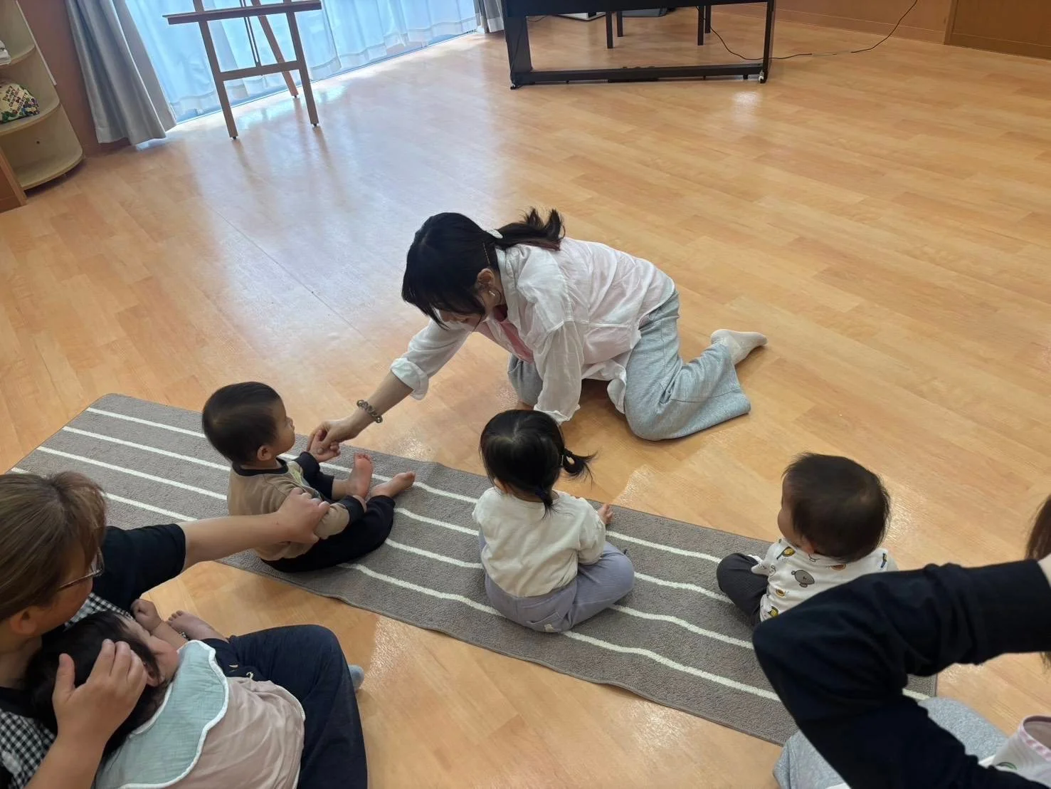 ピアノの鍵盤の横で先生が子どもの手首をやさしく支え、指の動きを見ている場面